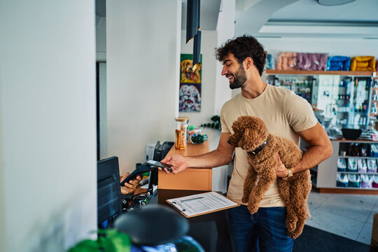 Man making contactless smartphone payment at pet shop