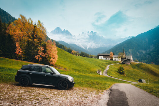 Car Parked on Scenic Alpine Hill with St Magdalena Church and Dolomites Mountain during Autumn in Italy