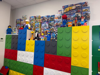Obraz premium Colorful giant toy brick wall with lego figures and boxed sets in a playroom.