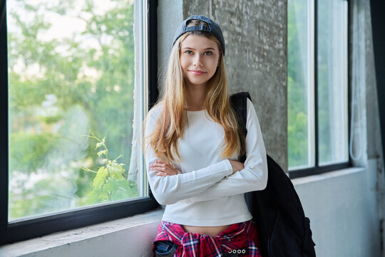Confident teenage girl student with backpack smiling with folded arms