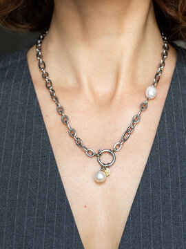 Stylish woman in tailored vest wearing pearl and steel chain - modern minimalist jewelry fashion portrait in natural light