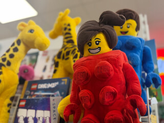 Obraz premium Colorful lego style plush toy figures on a store shelf, including a red minifigure and giraffe characters in a playful display