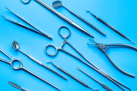 A lot of stainless surgical instruments and tools on blue table, top view. Medical background