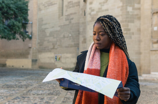 Young black woman exploring city with map