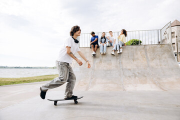 Obraz premium Teenager skateboarding with friends watching at skatepark