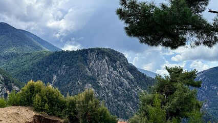 Mountain valley landscape with rocky ridge and pine trees under dramatic clouds, calm natural mood with fresh alpine air, ideal for travel nature and hiking themes © fotoworld