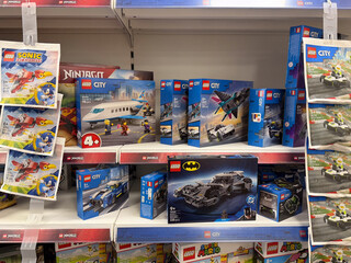 Obraz premium Colorful lego toy sets and licensed character boxes displayed on a retail store shelf in a toy aisle.
