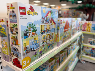 Fototapeta premium Row of lego duplo toy boxes on a store shelf in a colorful toy aisle, showing building sets for young children