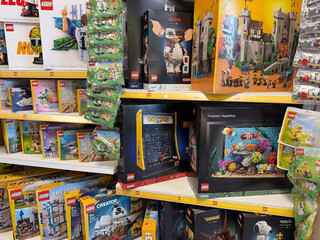 Fototapeta premium Colorful lego toy boxes displayed on store shelves in a retail aisle, showing building sets for kids and collectors