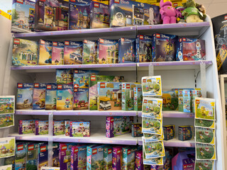 Obraz premium Toy store shelf filled with colorful lego disney and friends building set boxes on display in a retail aisle