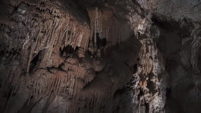 Stalactites and flowstone formations inside deep limestone cave system.
