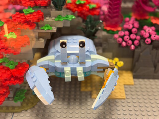 Fototapeta premium Colorful lego crab figure displayed in a playful garden scene with bright flowers and blocks, creative toy build for kids and collectors