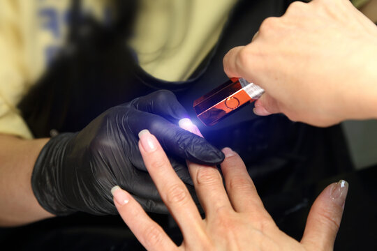 A woman's hand during a manicure. A woman getting a manicure. A manicurist is doing a client's nails at a nail salon. Manicure services. Nail art. Beauty salon.