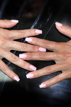 Receiving Professional Manicure in Modern Salon. Beautiful, well-groomed women's hands with elegant nails against a dark background. Beauty salon concept: manicures, pedicures. 