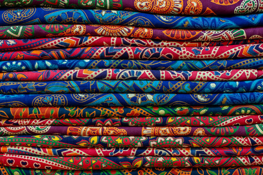 Brightly colored textile fabrics stacked together. Beautiful traditional oriental and Indian bohemian patterns on cotton material. Perfect for fashion retail, interior decor and textile design