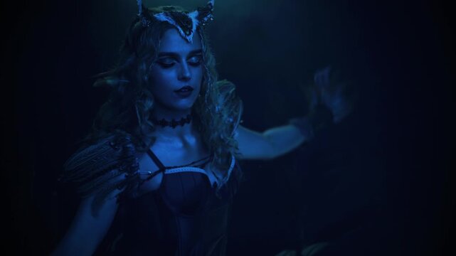 Fantasy characters fashion model posing dansing vawing hand flaps arms like wings. dark night forest moon light. evil gothic fairy woman owl, bird costume. sexy face fairy elf girl dancer performing.