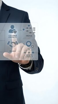 Businessman in dark suit holding transparent digital interface displaying customer centricity, engagement, and growth strategy icons for business development and marketing.