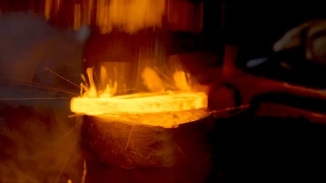 The blacksmith employs a powerful mechanical hammer to shape glowing metal on an anvil, followed by intense reheating within a coal fire furnace for further industrial forging operations.