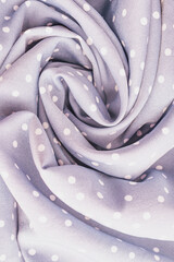 Vertical close up shot of a soft lavender purple polka dot fabric material texture twisted into a beautiful spiral rose pattern on a cozy comfortable blanket © moryachka