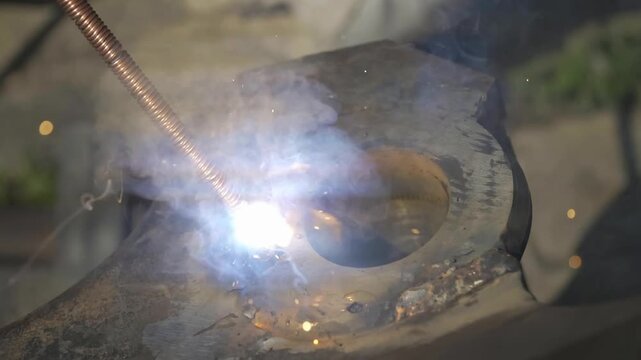 Industrial metal welding and slag removal techniques for repair processes that involve heating steel components with electrodes and chipping away residue for precise equipment maintenance tasks.