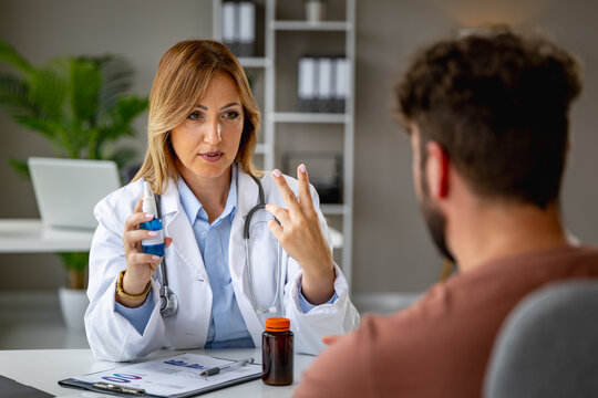 Caucasian female doctor explaining medication and nasal spray instructions to caucasian male patient during consultation