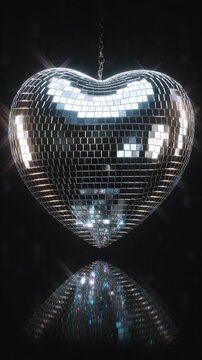 Shiny heart-shaped disco ball reflecting light in dark environment.
