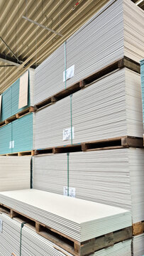 large stacks of drywall sheets stored in an industrial warehouse. concept of construction supplies