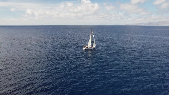 Sailboat moves smoothly in the Mediterranean sea with full sail during a close reach point of sail