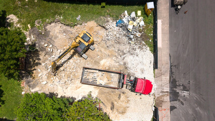 Obraz premium Aerial view of an excavator loading construction debris into a dump truck