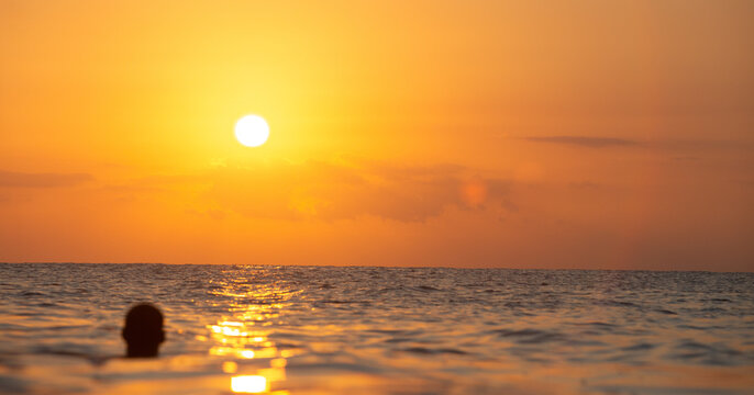 Person Silhouette Relaxing in Ocean Water Watching Beautiful Golden Sunset