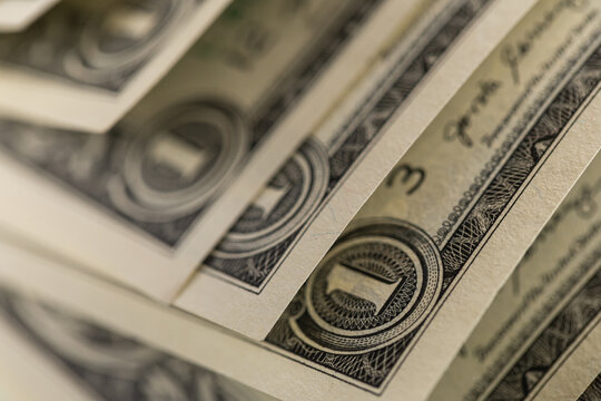 Macro shot of US one dollar bills curved in rows with selective focus on One Dollar text