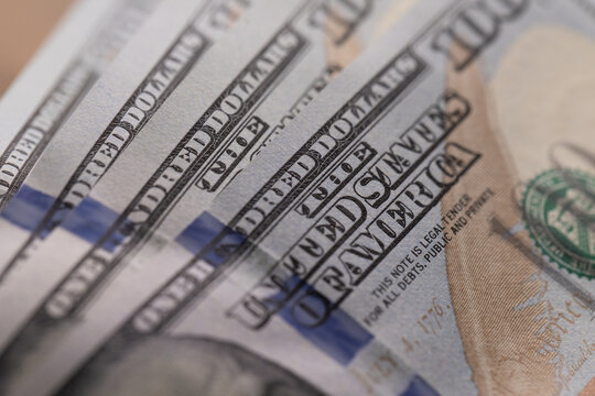 Close-up of US one hundred dollar bills stacked in diagonal rows with selective focus