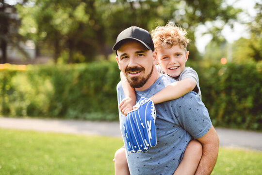Father and son playing baseball in sunny day at public park