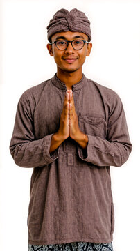 A man wearing glasses and a turban is smiling and holding his hands together in a prayer position