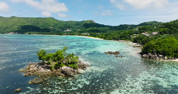 Turquoise lagoon featuring a small rocky islet surrounded by lush greenery. Seychelles, Mahe.