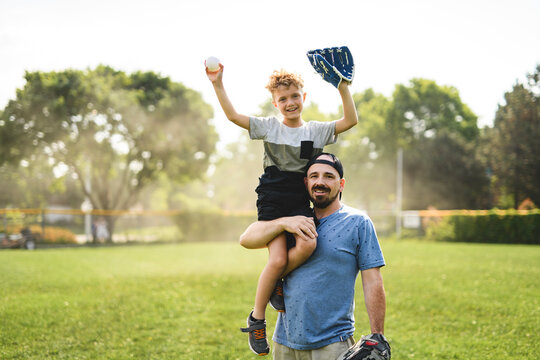 Father and son playing baseball in sunny day at public park