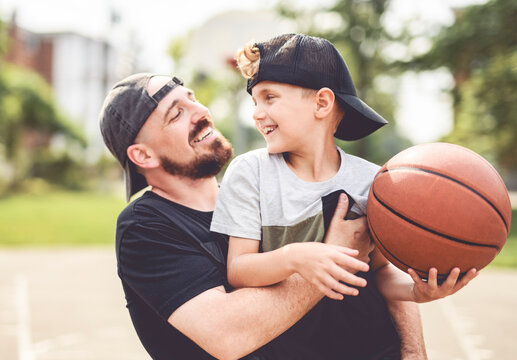 man and young boy playing basketball on a court, teaching little player and spending time outdoors