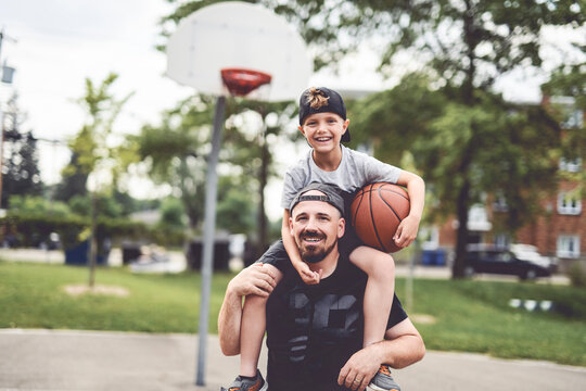man and young boy playing basketball on a court, teaching little player and spending time outdoors