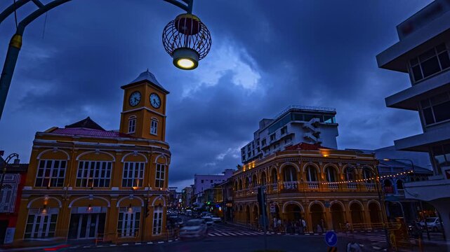 Time lapse Blue hour view of the historic clock tower in Phuket Old Town, Thailand, featuring beautifully preserved Sino-Portuguese architecture, dramatic clouds, and motion-blurred city traffic.