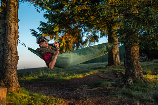 Man enjoying virtual reality experience in outdoor hammock