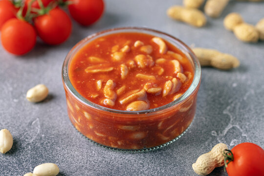 Peanuts in tomato sauce in glass bowl on the table