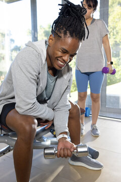 African American duo training in studio shorts man curling metal weight woman holding purple weight