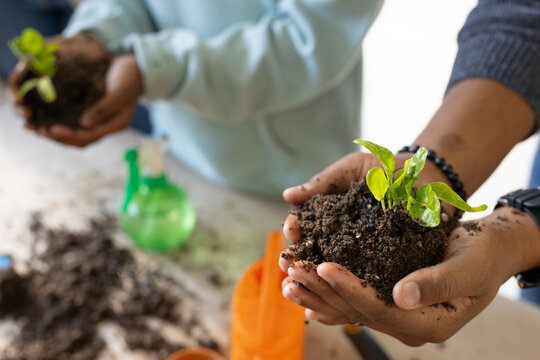 Group of three participants handling seedlings and soil at tabletop workshop with spray bottle