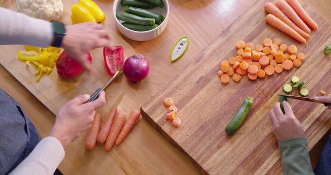 African American friends slicing pepper, carrots, zucchini on boards prepping meal at home