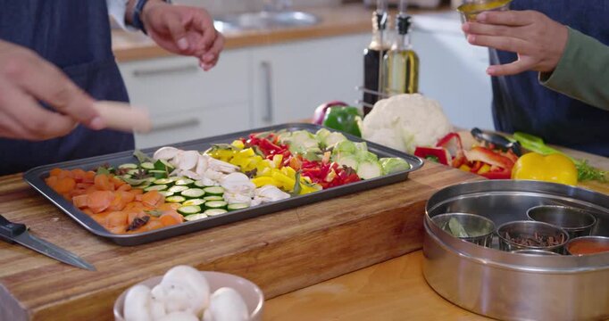 African American couple prepping tray on counter, woman starting spice tin herb pot before baking