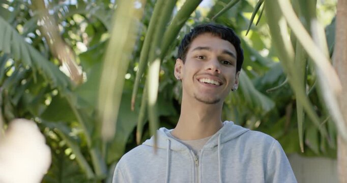 Focus pulling African American adult man smiling leaning among leaves in backyard reacting to focus