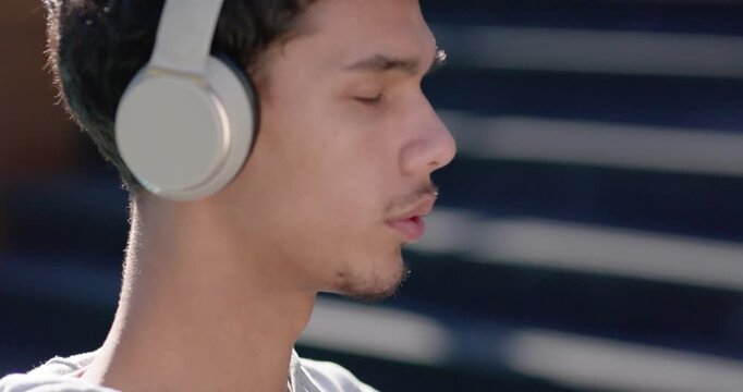African man listening to music via headphones, mouthing lyrics in hoodie by slats, copy space