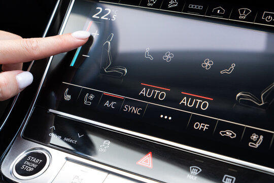 Woman finger pressing plus icon to increase temperature on car touch screen