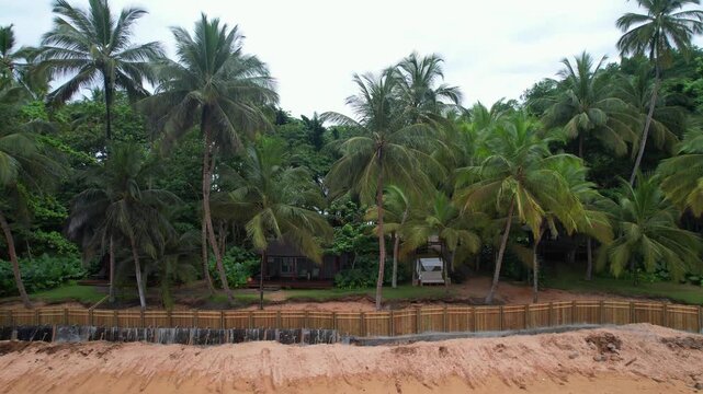 Flying sideways with a view of a beach house at Bom Bom resort and beach at Ilha do Principe,Sao Tome e Principe,Africa