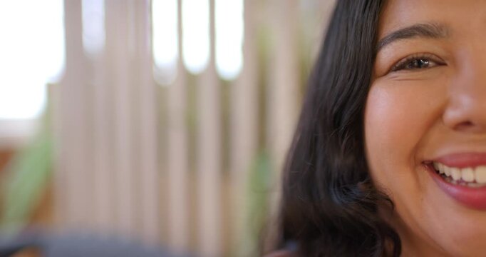 Adult woman smiling, widening into laugh at home by window with slatted divider and plant